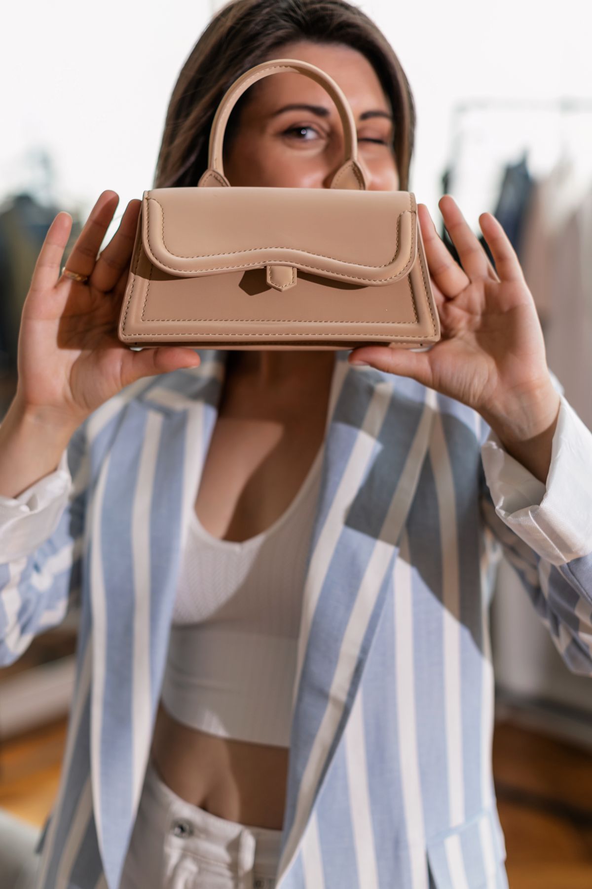 Woman presenting an elegant neutral handbag in a boutique